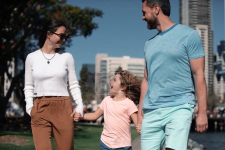 Téléchargez les photos : Parents avec fils marchant dans la ville. Famille faisant une promenade dans la rue - en image libre de droit