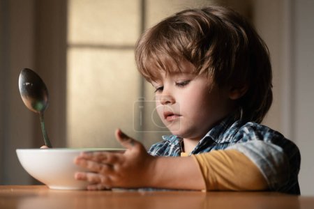Photo for Kid boy eating healthy food at home. Good morning in Happy family. Little boy sitting at the table and eating milk snack - Royalty Free Image