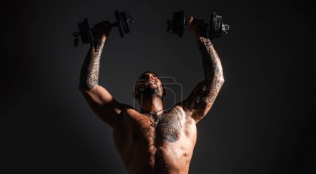 Photo for Strong man raising the dumbbells up. Intense workout. Body with tattoo - Royalty Free Image