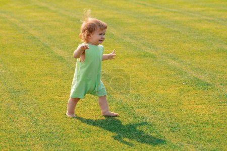 Photo for Baby in beautiful spring green field. Healthy child - Royalty Free Image