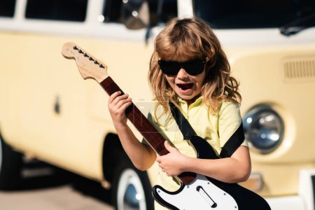 Téléchargez les photos : Enfant avec guitare. Portrait de garçon de 7 ans en plein air - en image libre de droit