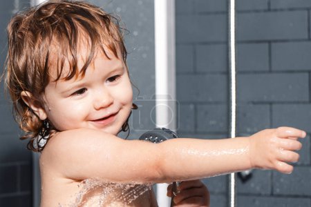 Téléchargez les photos : Laver l'hygiène infantile et les soins de santé. Visage de bébé dans le bain moussant. Joyeux bébé drôle baigné dans le bain - en image libre de droit