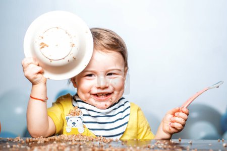 Foto de Bebé comiendo, cara divertida del bebé con el plato - Imagen libre de derechos