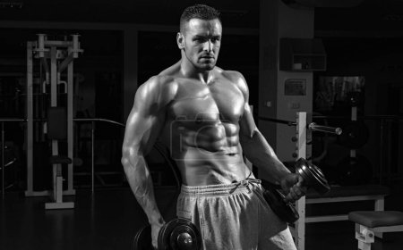 Foto de Cuerpo muscular de fitness. Entrenamiento de gimnasia. Hombre culturista haciendo ejercicios con mancuerna - Imagen libre de derechos