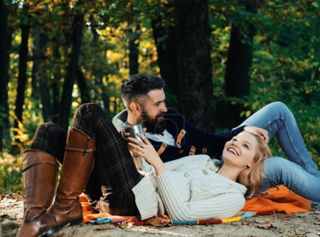 Foto de Pareja de otoño en el amor abrazo. Jóvenes amantes disfrutando el uno del otro en un picnic. Mujer acostada en la pierna del hombre y teniendo un momento romántico juntos. Hermoso otoño afuera. Pareja en amor - Imagen libre de derechos