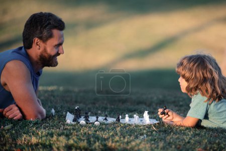 Téléchargez les photos : Père jouer aux échecs avec enfant fils. Famille hors jeu - en image libre de droit
