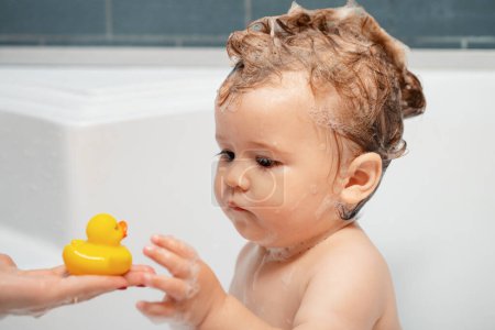 Foto de La niña se lava el pelo en el baño. Baño de burbujas infantil - Imagen libre de derechos