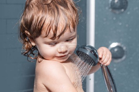 Téléchargez les photos : Petit bébé prenant son bain, portrait en gros plan d'un garçon souriant, soins de santé et hygiène des enfants. Bain d'enfant sous une douche - en image libre de droit