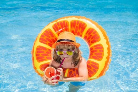 Téléchargez les photos : Enfant en lunettes de soleil et chapeau d'été boire cocktail d'été et flottant dans la piscine. Vacances d'été pour enfants. Enfants flottant dans la piscine d'eau. Enfants jouant et loisirs actifs, concept de piscine - en image libre de droit