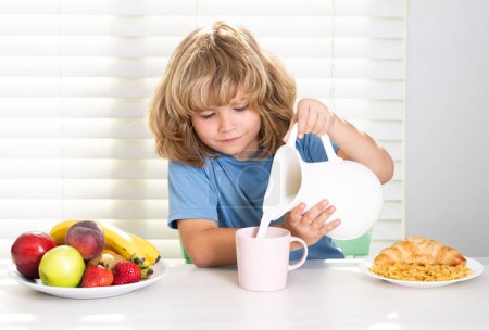 Photo for Kid pouring whole cows milk. Little child boy having healthy breakfast. Kids nutrition and development. Eating vegetables by child make them healthier - Royalty Free Image