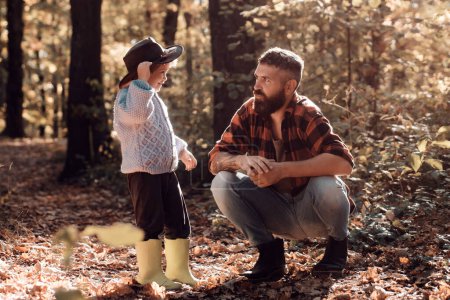 Foto de Kid y su padre están en el parque de otoño. Padre e hijo caminando durante las actividades de senderismo en el bosque de otoño al atardecer. - Imagen libre de derechos