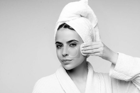 Téléchargez les photos : Portrait de jeune belle femme nettoie son visage du maquillage avec des tampons de coton. Soin de la peau et concept beauté - en image libre de droit