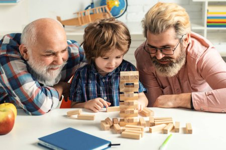 Photo for Boy pupil with father and grandfather. Three generations of men having fun together. Child happy. Happy three generations of men playing Jenga in class - Royalty Free Image