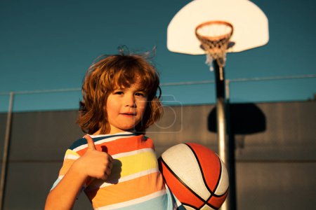 Photo for Cute child playing basketball. Portrait of sporty happy child, thumbs up - Royalty Free Image