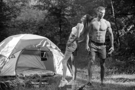 Foto de Loving young coupl near camp tent. Camping couple in love. Couples of lovers tourists relax on nature. Camping trip with lovers. Picnic for friends tourists - Imagen libre de derechos