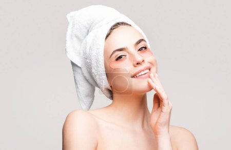 Photo for Happy woman applying eye patches. Close up portrait girl with towel on head. Portrait of beauty woman with eye patches showing an effect of perfect skin - Royalty Free Image