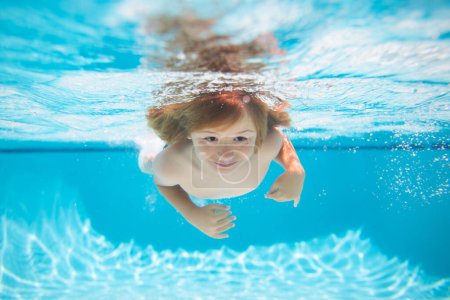 Téléchargez les photos : Petit garçon nageant sous l'eau sur la plage en mer en été. De l'eau bleue. Enfant garçon nageant en mer. Activités estivales pour enfants, sports nautiques - en image libre de droit