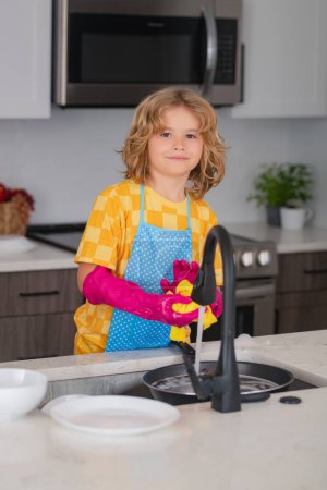 Photo for Clean dishes. Cute kid help in washing dishes at kitchen. Kid cleaning of kithen help with housework. Cute child boy housekeeping, child clean house - Royalty Free Image