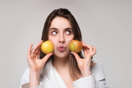 Téléchargez les photos : Femme aux pommes. Portrait d'une jeune femme joyeuse mangeant des pommes isolées sur fond gris - en image libre de droit