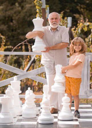 Photo for Grandfather and son playing chess on big chess board. Weekend with granddad - Royalty Free Image