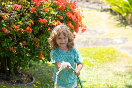 Photo for Happy little boy having fun in domestic garden. Child hold watering garden hose. Active outdoors games for kids in the backyard during harvest time. - Royalty Free Image