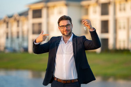 Photo for Real estate agent hold money dollars and house keys. Real estate sdemonstrating keys. Buying new home. Handsome real estate agent in suit showing the house for sale - Royalty Free Image