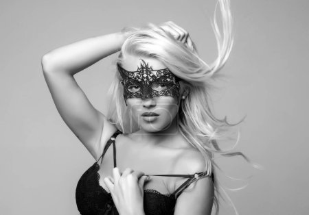 Foto de Foto de moda de una mujer hermosa con máscara de encaje en su cara, posando en el estudio. Mujer pelirroja hermosa con máscara de encaje - Imagen libre de derechos