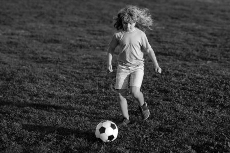 Foto de Niño de fútbol. Los niños juegan al fútbol en el estadio de verano. Niño pateando la pelota. Niño pequeño disparando a la portería, niño pateando pelota de fútbol - Imagen libre de derechos