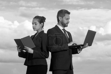 Photo for Businessman and businesswomen. Beautiful young business woman and handsome businessman in formal suits are using a laptop standing outdoor - Royalty Free Image