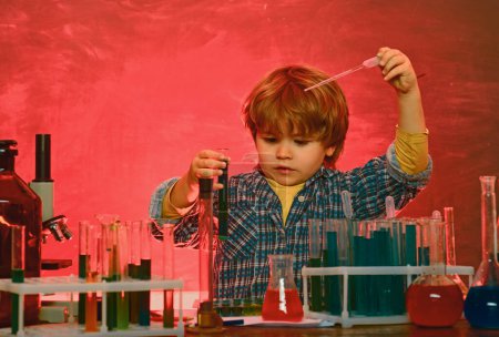 Photo for Back to school and happy time Kid is learning in class on background of blackboard. Chemistry lesson. Lab microscope and testing tubes - chemistry demonstration. - Royalty Free Image