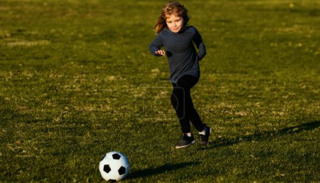 Foto de Soccer kid. Kids play football on summer stadium field. Little child boy kicking ball. Football sport training for children. Kid kicking a football ball on a grass - Imagen libre de derechos