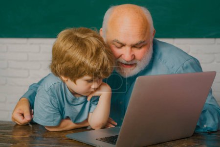 Photo for Young boy doing his school homework with his father. Old teacher. I love our moments in the school - remember time. Concept of education and teaching - Royalty Free Image
