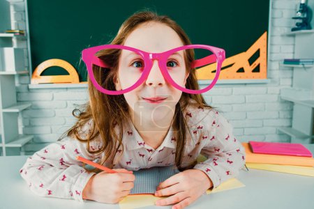 Photo for Funny pupil with glasses, home kids schooling. Child boy education concept. Cute pupil in classroom with funny face schooling work - Royalty Free Image