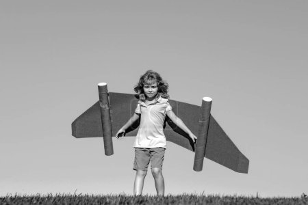 Téléchargez les photos : Enfant imagination, enfant pilote avec des ailes en papier s'amusant à l'extérieur. Vacances d'été et concept de voyage - en image libre de droit