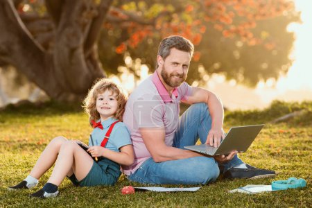 Photo for New normal back to school. Elementary scholar pupil sitting with teacher on grass - Royalty Free Image