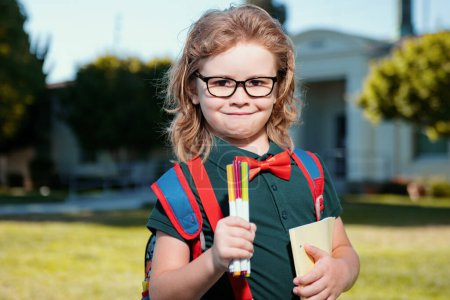 Foto de Gracioso chico nerd. Concepto de niño escolar. Alumno lindo, niño en uniforme escolar con mochila al aire libre. Retrato de colegial nerd - Imagen libre de derechos