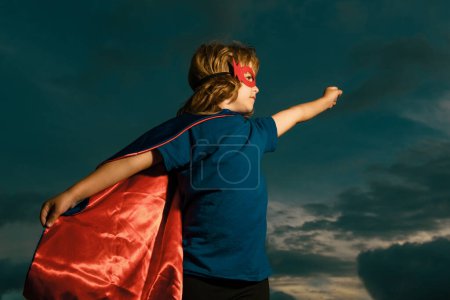 Kid having fun outdoors in super man cloak. Boy playing superhero. Success and winner concept