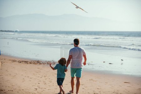 Photo for Dad and child enjoying outdoor. Father and son walking on sea - Royalty Free Image