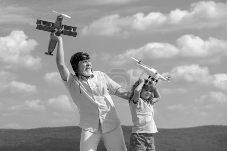 Photo for Child boy and grandfather with plane and quadcopter drone over blue sky and clouds background. Men generation granddad and grandchild - Royalty Free Image