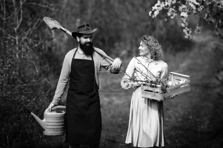 Téléchargez les photos : Concept de Terre. Image de deux fermiers heureux avec des instruments. Un fermier et sa femme debout dans leur champ. Couple d'agriculteurs travaillant dans le champ - en image libre de droit