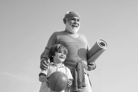 Foto de El abuelo y el niño hacen deporte al aire libre. Feliz hombre mayor en forma haciendo ejercicio. Vida sana y concepto deportivo. Estar en movimiento - Imagen libre de derechos