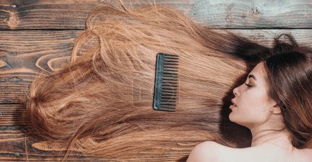 Foto de Mujer con hermoso pelo largo sobre fondo de madera. Cabello largo. Hermosa mujer para colorear cabello. Corte de pelo de moda - Imagen libre de derechos