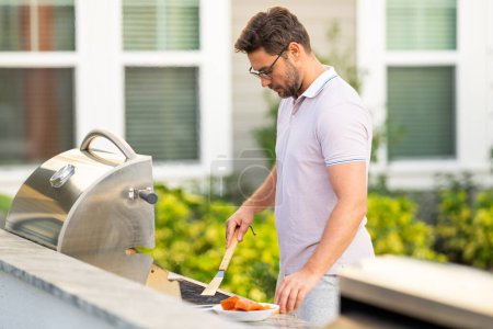 Photo for Handsome man preparing barbecue grill outdoor. Man cooking tasty food on barbecue grill at backyard. Chef preparing food on barbecue. Millennial man grilling meat on grill. Bbq party. Meal grilling - Royalty Free Image