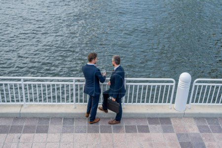 Photo for Two business men discussing outdoor during business meeting. Businessmen talking. Brainstorm with serious colleague. Confident business partners walking on street. Business partners talking - Royalty Free Image