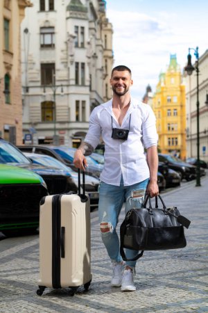 Foto de Concepto de viaje. Hombre viajero con bolsa de viaje al aire libre. Retrato de hombre joven caucásico en camisa en vacaciones de verano - Imagen libre de derechos