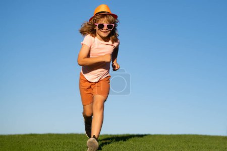 Téléchargez les photos : Activité sportive saine et course pour les enfants. Petit garçon à la course. Enfant s'amuser et courir sur l'herbe verte près du ciel bleu dans le parc - en image libre de droit