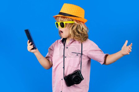 Photo for Kid traveller. Cute child takes picture with camera and phone. Traveller kid boy chatting on phone. Vacation travel lifestyle - Royalty Free Image