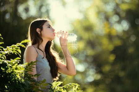 Foto de Una mujer sana bebiendo agua de la botella. Mantenga el concepto de hidratación. Sin esconder. Unidad con la naturaleza, al aire libre - Imagen libre de derechos