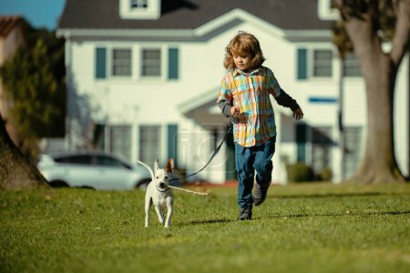 Foto de Niño pequeño compitiendo con el perro. Niño encantador con cachorro caminando al aire libre - Imagen libre de derechos