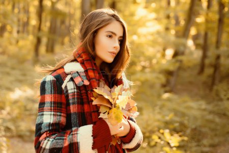 Photo for Carefree young woman in trendy vintage red pullover or sweater. Outdoor fashion photo of young beautiful lady surrounded autumn leaves. Autumn landscape - Royalty Free Image